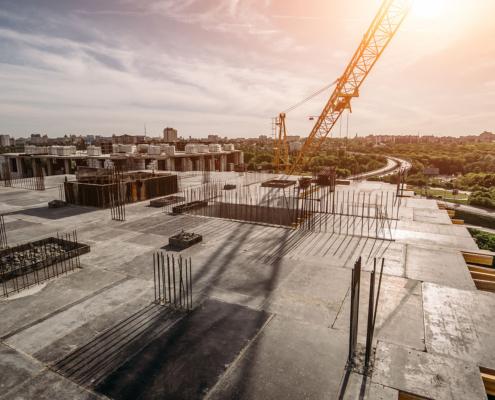Roof of construction site of new multi-storey residential building, industrial construction crane and other industry equipment